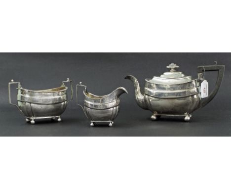 George III three piece silver tea service of squared boat shaped form, engraved with a family Crest, the milk jug and sucrier