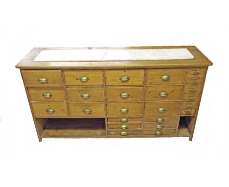 Vintage pine counter unit, the plain top inset with white marble surface (at fault) over an arrangement of twelve large drawe