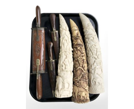 A group of Eastern carving knives in wooden sheathes and three resin tusk-style ornaments.