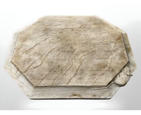 A Robert 'Mouseman' Thompson of Kilburn hexagonal oak bread board, with carved mouse signature, width 30 cm.