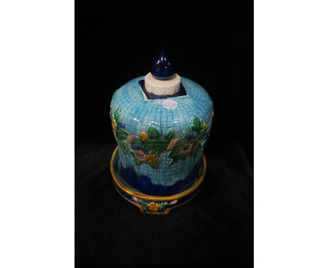 A GEORGE JONES STYLE GLAZED POTTERY COVER ON STAND, the light and dark blue ground moulded in relief with flowerheads and fol