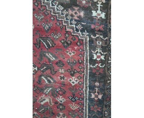 A WOOL RUG, the brown field with central floral panel within a conforming border,274cms x 183cms