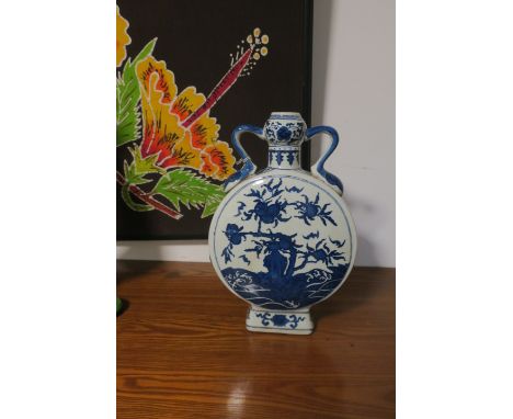 AN ORIENTAL GLAZED PORCELAIN MOON FLASK the white ground decorated with blue foliates with a pair of scrolled handles on rect