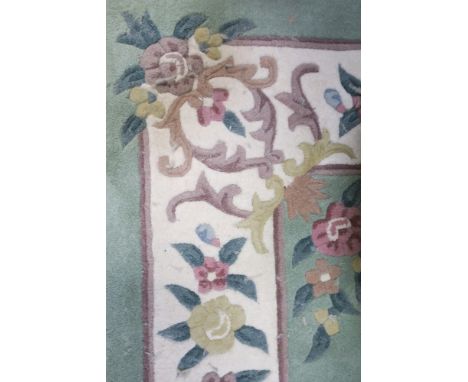 A RECTANGULAR WOOL RUG the green ground decorated with flower heads with a central green panel flanked by a white border  296