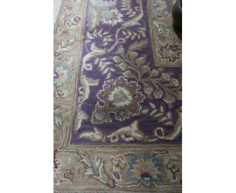 A RECTANGULAR WOOL RUG the central cream panel filled with gold foliates within a mauve foliate filled border  346cm x 246cm 