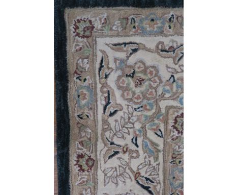 A RECTANGULAR WOOL RUG the cream ground with a rectangular green foliate filled panel with graduating conforming borders  240