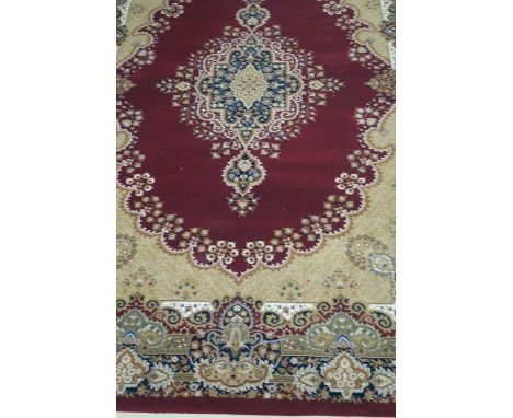 A RECTANGULAR WOOL RUG, the wine ground filled with foliate filled rectangular panel and gold borders, white fringing, 283cms