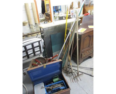 A mixed lot of tools to include garden tools, saws, forks, hoes, spanners and other hand tools, together with a metal trunk