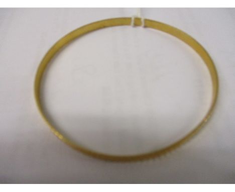 A Middle Eastern yellow metal bangle with line cut decoration