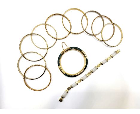 Nine gold coloured bangles 85.0gms, a yellow metal jade green bangle 27gms, and a 18ct gold plated white jade articulated bra