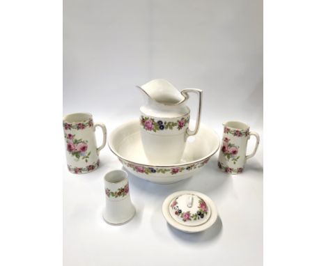 A Burslem jug, basin, lidded soap dish and brush holder, two other jugs with roses pattern.