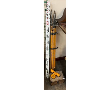 A surveyor's sight on a tripod and a measuring stick 