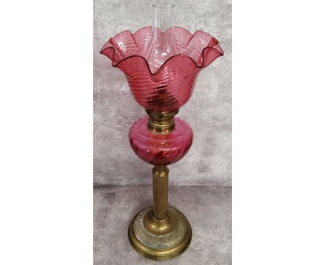 A 19th century French cranberry glass and brass table oil lamp by Gaudard, with wavy ribbed shade above blown reservoir, flut