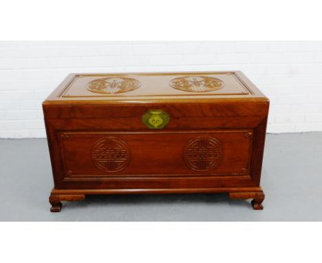 An Eastern rosewood trunk, the rectangular hinged top and front with oriental motifs, with a brass work clasp on carved suppo