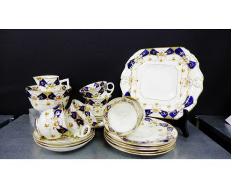 A Beswick & Sons porcelain teaset with gilt rims and cobalt blue borders with small floral sprays comprising two cake plates,