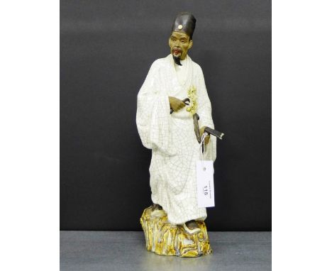 A Craquelure glazed Japanese male figure, modelled standing in traditional dress carrying an axe on a naturalistic base, 38cm