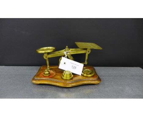 A pair of brass postal scales with weights on a shaped wooden base