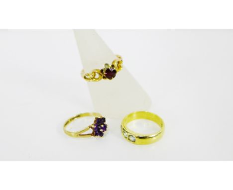 A collection of three gold gemset dress rings to include an 18ct gold ring set with three pale blue stones, a 9ct amethyst cl