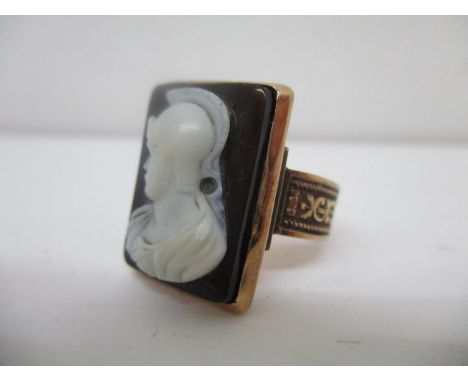 A 19th century gold coloured metal ring set with a carved cameo panel of a Roman soldier with scroll engraved panels to the s