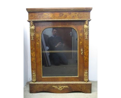 A late Victorian walnut pier cabinet with gold painted metal mounts and floral marquetry, the glazed, panelled door enclosing