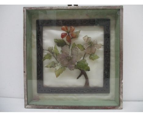 A 20th century Chinese jade and carved stone model of a flowering branch within a carved and pierced hardwood frame on a silk