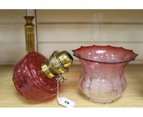 A cranberry glass oil lamp and shade on brass column