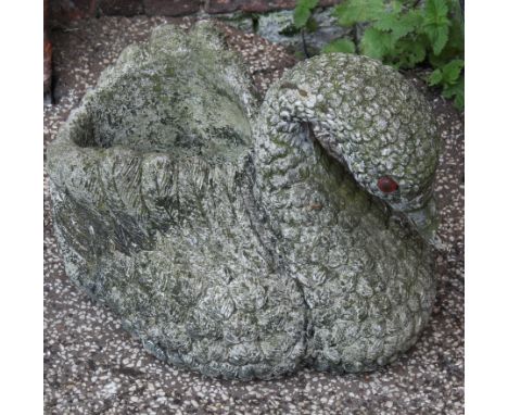 A weathered concrete swan planter