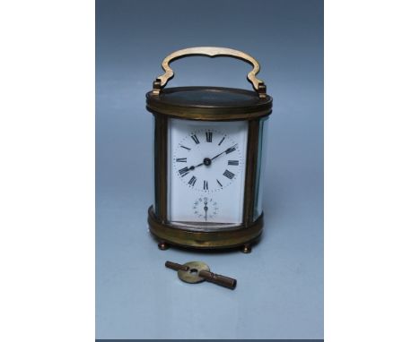 A FRENCH OVAL BRASS CASE CARRIAGE CLOCK, white enamel dial with Roman numerals and outer minute markers, subsidiary dial belo