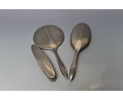 A HALLMARKED SILVER ART DECO STYLE DRESSING TABLE SET - BIRMINGHAM 1960,  consisting of a hand mirror and two brushes, each w