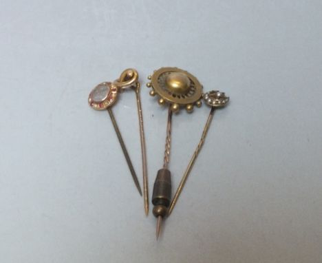 A COLLECTION OF FOUR YELLOW METAL STICK PINS, comprising a moon and stars pin set with seed pearls, a circular pin with centr