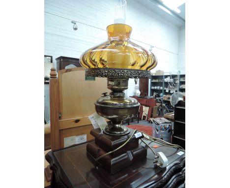 A table lamp in the style of an oil lamp with amber glass shade