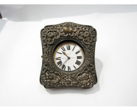 An embossed silver travelling clock case together with a Finnigans of Manchester 8 day clock 