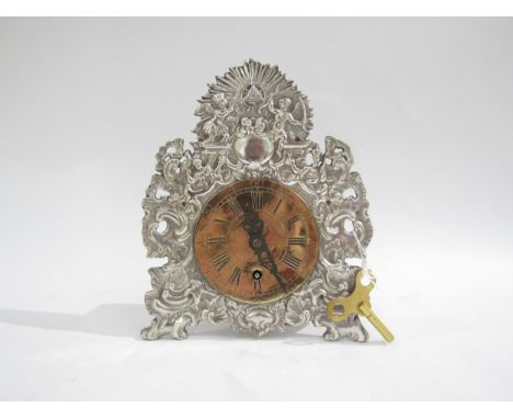 A German mantel timepiece, baroque style repousse silver plated front with brass dial 3.5". 8.5" high, with key. Signed A.Jag