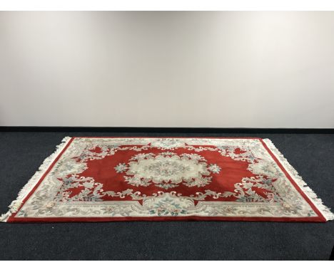 A fringed embossed Chinese carpet on red ground, 290cm by 183cm