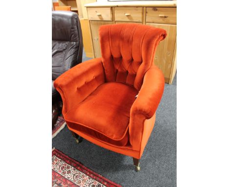 An Edwardian armchair in red/orange button fabric 
