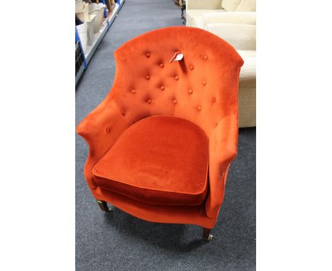 An Edwardian armchair in red/orange button fabric 
