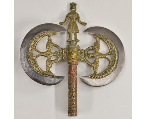 An Indian steel, brass and copper axe head weapon, crescent shaped blades, figural finial above a mask flanked by birds, 25.5