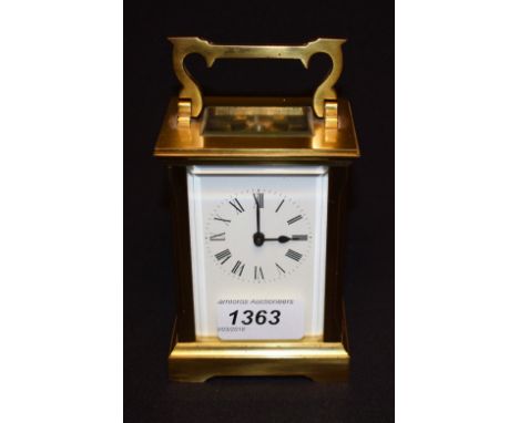 A lacquered brass carriage clock, white rectangular enamel dial, Roman numerals, swing handle, stepped base, bracket feet, 15