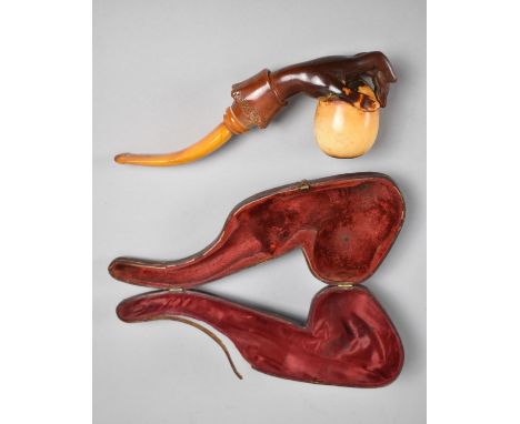 A 19th Century Cased Amber and Meerschaum Pipe Modelled as a Hand Holding an Egg, 21cms Long 