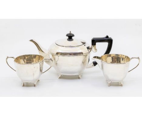 A George VI silver three piece tea service comprising teapot, sugar bowl and milk jug, the teapot with ebonised handle and fi