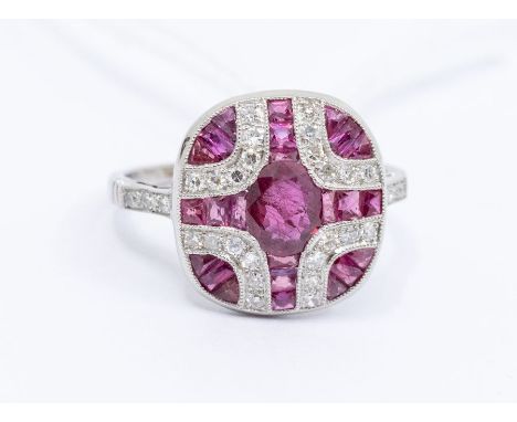 A ruby and diamond platinum dress ring, comprising an oval cut ruby to the centre and calibre/French cut rubies cross shaped 