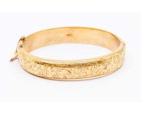 A 9ct gold hinged bangle, hollow form with engraved foliate decoration, width approx. 12mm, inner diameter approx. 62mm, weig