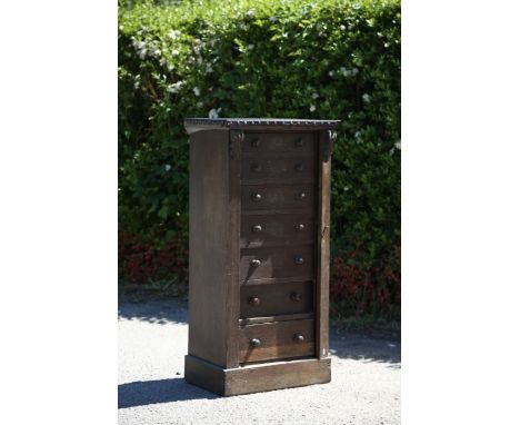 A mid Victorian oak Wellington chest, comprising seven short graduated drawers, with a single central locking mechanism, carv