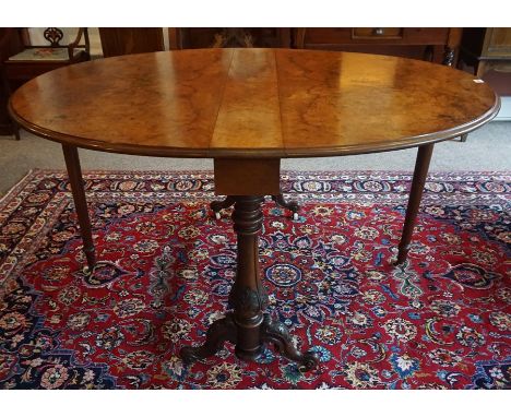 A Victorian Figured Walnut Centre Table, With D shaped drop ends, raised on scroll and plain supports, terminating on ceramic