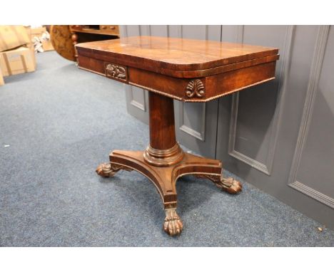 A Georgian rosewood card table, with turn-over top, carving to apron, raised on turned column tempinating in platform upon pa