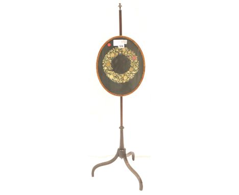 A Regency period mahogany and walnut framed pole-screen with oval embroidered silk panel raised on a tripod base, overall H: 