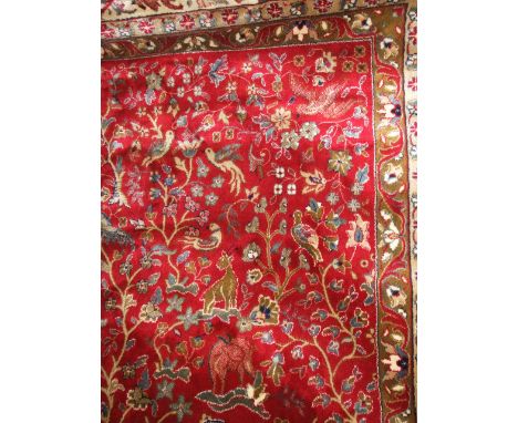 A Persian style wool carpet with red ground field with multi floral decoration within wide banded running borders, 380cm x 24