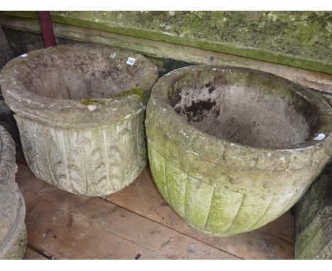 A weathered but contemporary composition stone garden planter of circular form with acanthus detail together with one other i