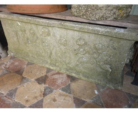 A weathered cast composition stone planter of rectangular form with cherub relief detail, 90 cm long x 40 cm wide x 33 cm in 