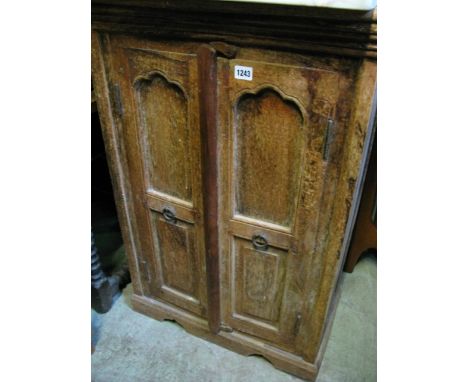 A small Indian hardwood side cupboard, freestanding and enclosed by a pair of twin panelled doors with iron ring pull handles
